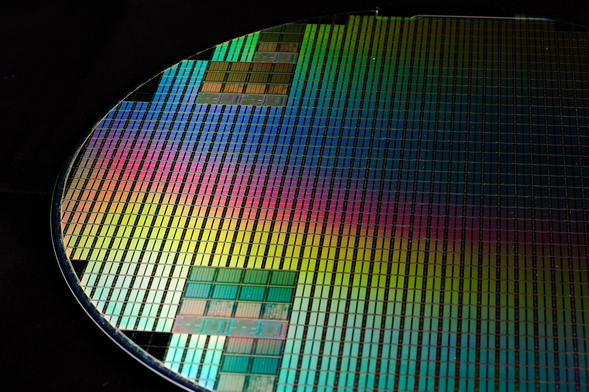 Silizium-Wafer mit irisierenden Reflexionen und Die-Grid auf schwarzem Grund